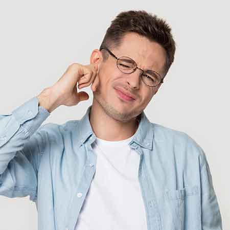 Man plugging his ear to try to stop ringing in his ears.